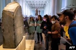 FILE - Visitors view the Rosetta Stone at the British Museum in London on July 26, 2022. (Photo by Amir MAKAR / AFP)