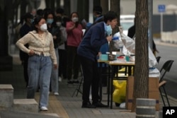 Residents line up to get their routine COVID-19 throat swabs at a coronavirus testing site setup along a pedestrian walkway in Beijing, China, Oct. 13, 2022.