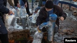 A man fills a container as local residents queue for water after about 80% of the Kyiv's inhabitants were left without water, after a Russian missile attack, Oct. 31, 2022. 