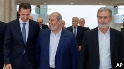 In this photo released by the Syrian news agency SANA, Syrian President Bashar Assad, left, speaks with Khalil al-Hayeh, a senior figure in Hamas' political branch, and Ziad Nakhaleh, leader of Palestinian Islamic Jihad group in Damascus, 19, 2022. 