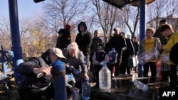 Жители на Киев полнат пластични садови и шишиња на пумпа за вода во еден од парковите во украинскиот главен град Киев вчера 