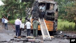 People inspect a bus that caught fire on a highway in Nashik, in the western Indian state of Maharashtra, Oct. 8, 2022.