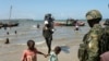 Un soldat rwandais regarde des pêcheurs revenir sur le rivage à Mocímboa da Praia, dans la province de Cabo Delgado, au Mozambique, le 27 septembre 2022.