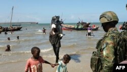 Un soldat rwandais regarde des pêcheurs revenir sur le rivage à Mocímboa da Praia, dans la province de Cabo Delgado, au Mozambique, le 27 septembre 2022.