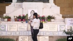 FILE - Mandy Mallia, sister of late journalist Daphne Caruana Galizia, lights candles in front of a picture of her sister in Valletta, Malta, Oct. 14, 2022.