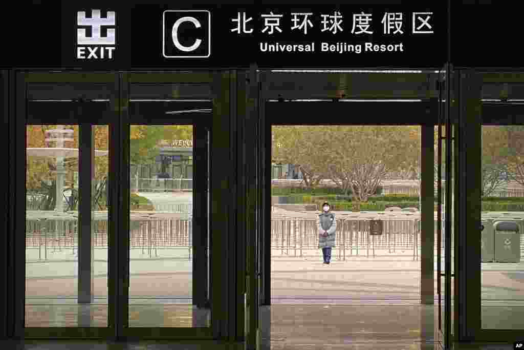 A worker wearing a face mask stands outside an exit from a subway station to stop visitors from going to the Universal Studios Beijing resort, which according to a notice was closed for epidemic control, in Beijing, China.