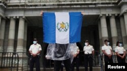 Un manifestante levanta una bandera de Guatemala en el exterior del Palacio Nacional de Cultura durane una protesta contra la corrupción en la Ciudad de Guatemala el 11 de agosto de 2022.