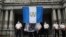 Un manifestante levanta una bandera de Guatemala en el exterior del Palacio Nacional de Cultura durane una protesta contra la corrupción en la Ciudad de Guatemala el 11 de agosto de 2022.
