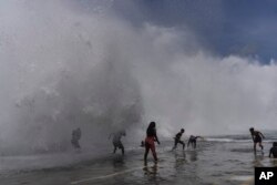 People play in the breaking waves at the Malecon, in the aftermath of Hurricane Ian in Havana, Cuba, Thursday, Sept. 29, 2022. (AP Photo/Ramon Espinosa)