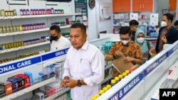 Sejumlah petugas kepolisian mendatangi sebuah apotek di Banda Aceh, pada 24 October 2022. Mereka memeriksa keberadaan obat sirop yang mengandung zat berbahaya menyusul perebakan kasus gagal ginjal akut di Indonesia. (Foto: AFP/Chaideer Mahyuddin)