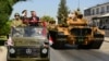 FILE - Turkish Cypriot leader Ersin Tatar, stands on a military vehicle, right, as he reviews the military parade marking the 48th anniversary of the 1974 Turkish invasion in the Turkish occupied area of the divided capital Nicosia, Cyprus, July 20, 2022.