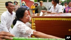 The mother of Son Sophat, a teen victim of a boat accident, cries by her daughter's coffin during a funeral procession in Koh Chamroeun village, eastern Phnom Penh, Cambodia, Oct. 14, 2022. 