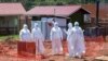 FILE - Doctors walk inside the Ebola isolation section of Mubende Regional Referral Hospital, in Mubende, Uganda, Sept. 29, 2022.