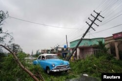 A vintage car passes by debris caused by the Hurricane Ian as it passed in Pinar del Rio, Cuba, Sept. 27, 2022.