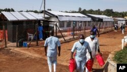 FILE - Medical attendants walk outside the Ebola isolation section of Mubende Regional Referral Hospital, in Mubende, Uganda, Sept. 29, 2022.