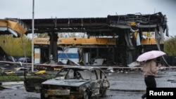 A woman passes by a gas station destroyed by yesterday's Russian military strike, in Dnipro, Ukraine, Oct. 26, 2022. 