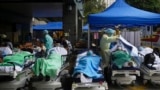 Patients lie on hospital beds as they wait at a temporary makeshift treatment area outside Caritas Medical Centre in Hong Kong, where hospitals reached 90% capacity and COVID-19 quarantine facilities were at their limit, authorities said.