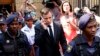Olympic and Paralympic track star Oscar Pistorius (C) uses his phone as he leaves the first day of his sentencing at North Gauteng High Court in Pretoria, Oct. 13, 2014.