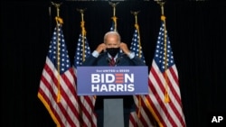 Democratic presidential candidate former Vice President Joe Biden removes his face mask as he arrives to speak at the Hotel DuPont in Wilmington, Del., Aug. 13, 2020. 