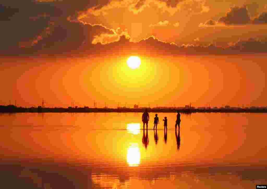 People enjoy the sunset on the bed of a drained area of the Sasyk-Sivash lake near the settlement of Pryberezhne (Pribrezhnoye), Crimea, Aug. 22, 2020.