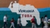 Gente pasa frente a un mural en Caracas, donde se ve un mapa venezolano en el que está anexada la Guayana Esequiba, el 6 de abril de 2024. El gobierno de Nicolás Maduro entregó un documento ante la Corte Internacional de Justicia para defender su potestad sobre ese territorio.