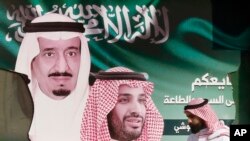 Seorang pria membawa makanannya saat dia berjalan melewati spanduk yang menunjukkan Raja Saudi Salman, kiri, dan Putra Mahkota Mohammed bin Salman, di Jiddah, Arab Saudi, 12 November 2019. (Foto: AP)