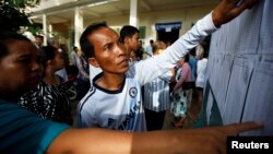 People look through the voters' list after a polling station opened for the general elections in Kandal province, file photo. REUTERS/Damir Sagolj