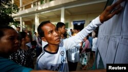 People look through the voters' list after a polling station opened for the general elections in Kandal province July 28, 2013.