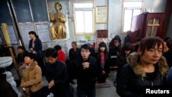 FILE - Believers take part in a weekend mass at an underground Catholic church in Tianjin.