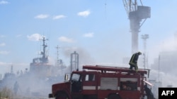 На фотографии, опубликованной Telegram-каналом Одесского горсовета 24 июля 2022 года, видно, как украинские пожарные тушат горящий катер в Одесском порту после попадания ракет 23 июля 2022 года