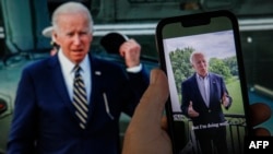 En esta composición del 21 de julio de 2022, un tuit de video del presidente Joe Biden se observa en un teléfono celular junto a una pantalla de computadora con el aviso de que dio positivo a una prueba de COVID-19. 