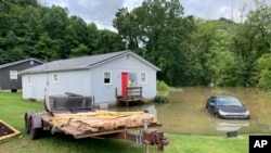 A woman glances at her phone after carrying supplies into her home in Jackson, Ky., July 29, 2022.