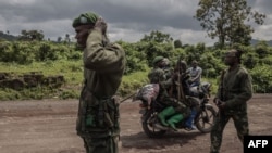 FILE - A motorcyclist carries soldiers as others patrol the area in Kibumba that was attacked by M23 rebels in clashes with the Congolese army, near the town of Goma in eastern Democratic Republic of Congo, June 1, 2022.