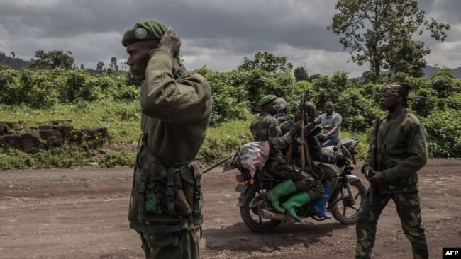 FILE - A motorcyclist carries soldiers as others patrol the area in Kibumba that was attacked by M23 rebels in clashes with the Congolese army, near the town of Goma in eastern Democratic Republic of Congo, June 1, 2022.