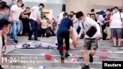 FILE - Plainclothes security personnel drag a demonstrator down stairs during a protest over the freezing of deposits by some rural-based banks, outside a People's Bank of China building in Zhengzhou, China, July 10, 2022, in a video screengrab obtained by Reuters.