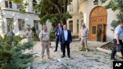 In this handout photo released by Sevastopol governor Mikhail Razvozhaev's Telegram channel July 31, 2022, Razvozhayev, center, stands at the scene of explosion at the headquarters of Russia's Black Sea Fleet in Sevastopol, in Russia-annexed Crimea. 