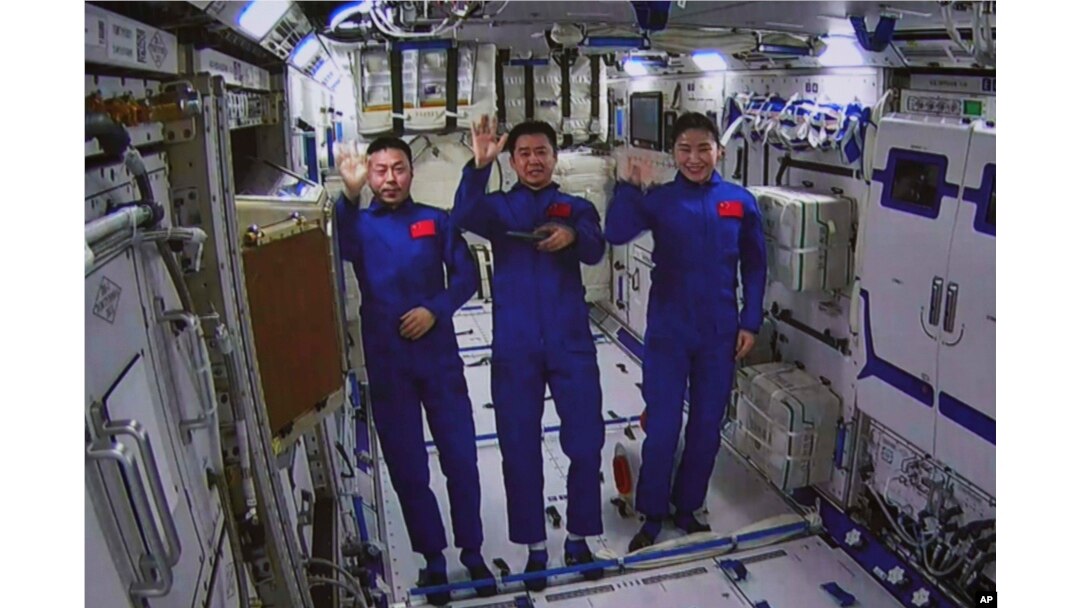 Dalam foto yang dirilis oleh Xinhua News Agency ini, gambar yang diambil dari layar di Pusat Kontrol Dirgantara Beijing menunjukkan astronot China dari kiri, Cai Xuzhe, Chen Dong dan Liu Yang melambaikan tangan dari dalam modul lab Wentian, Senin, 25 Juli 2022. (Guo Zhongzheng/Xinhua via AP)