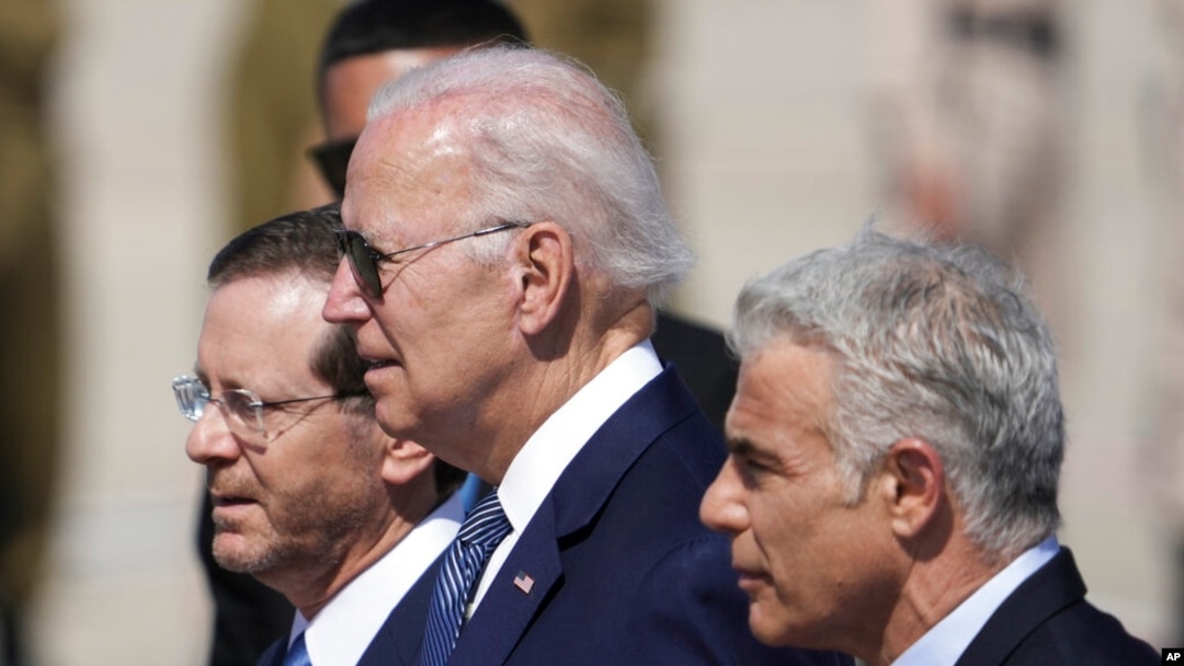 Presiden Joe Biden, tengah, Presiden Israel Isaac Herzog, kiri, dan Perdana Menteri Israel Yair Lapid, berjalan saat upacara penyambutan ketika Biden tiba di Bandara Ben Gurion, dekat Tel Aviv, Israel, Rabu, 13 Juli 2022. (Foto: AP )