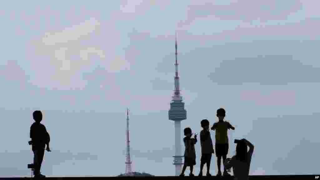 Children are seen standing against the sky and the iconic N Seoul Tower at the National Museum of Korea in Seoul, South Korea.