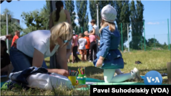 Sukarelawan Kyiv, Anastasia Karpeeva, membantu seorang anak untuk membuat karya seni. (VOA-videograb)