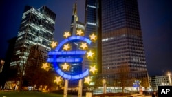 FILE - A man walks past the Euro sculpture in Frankfurt, Germany, March 11, 2021. 