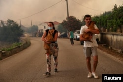 Ljudi nose pse za vrijeme evakuacije u mestu Leiria u Portugalu 13. jula 2022.