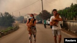 Ljudi nose pse za vreme evakuacije u mestu Leiria u Portugalu 13. jula 2022.
