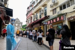 FILE: People line up to be tested for the coronavirus that causes COVID-19 near the Ruins of Saint Paul's in Macao, China, June 20, 2022.