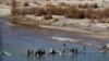 FILE - Afghans try to repair a dam on a river as seen from the British forces forward operating base Sterga II at Helmand province in southern Afghanistan, Dec. 16, 2013.