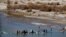 FILE - Afghans try to repair a dam on a river as seen from the British forces forward operating base Sterga II at Helmand province in southern Afghanistan, Dec. 16, 2013.