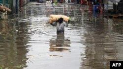A vendor carrying a sack of leafy vegetables wades across a flooded market place after heavy rainfall in Lahore, Pakistan.
