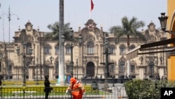 Un trabajador barre una calle frente al palacio de gobierno en Lima, el 15 de noviembre de 2020.