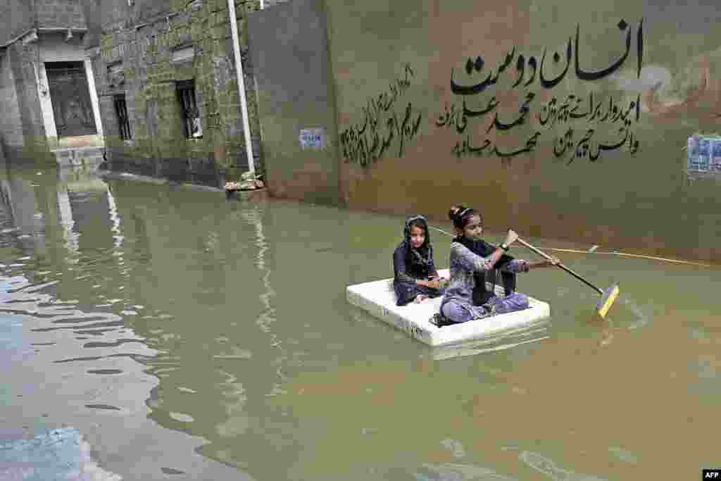 Girls use a temporary raft across a flooded street in a residential area after heavy monsoon rains in Karachi, Pakistan.