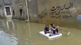 Girls use a temporary raft to cross a flooded street in a residential area after heavy monsoon rains in Karachi, Pakistan.